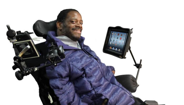 Photo of man in wheelchair with iPad assistive devices