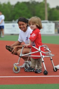 Photo of child with walker and "buddy" playing baseball