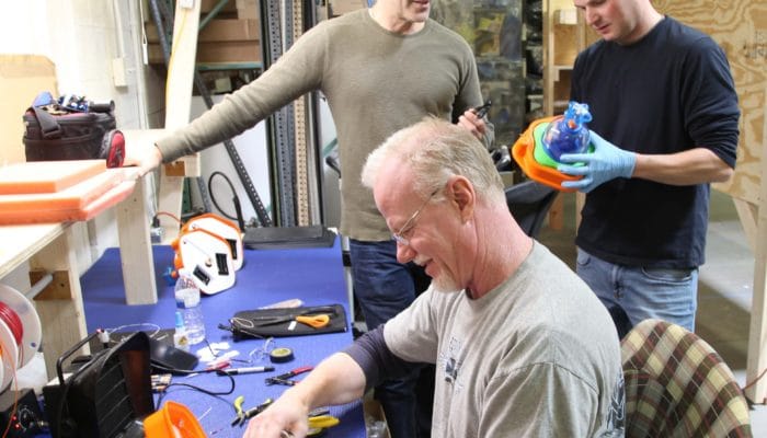 Three Enabling Devices employees building new products in our manufacturing facility