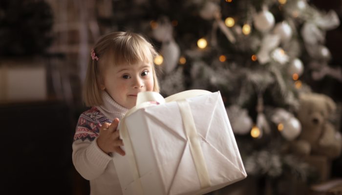 Young Girl with Christmas Present next to a Christmas Tree