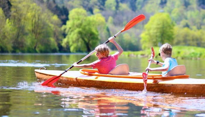 Two Boys Paddling in a Kayak on a Lake